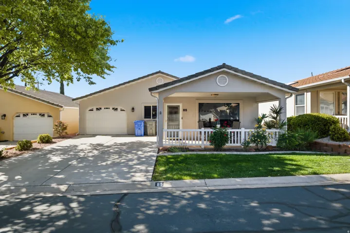 Ranch-style house with an attached garage, a porch, stucco siding, driveway, and a front yard