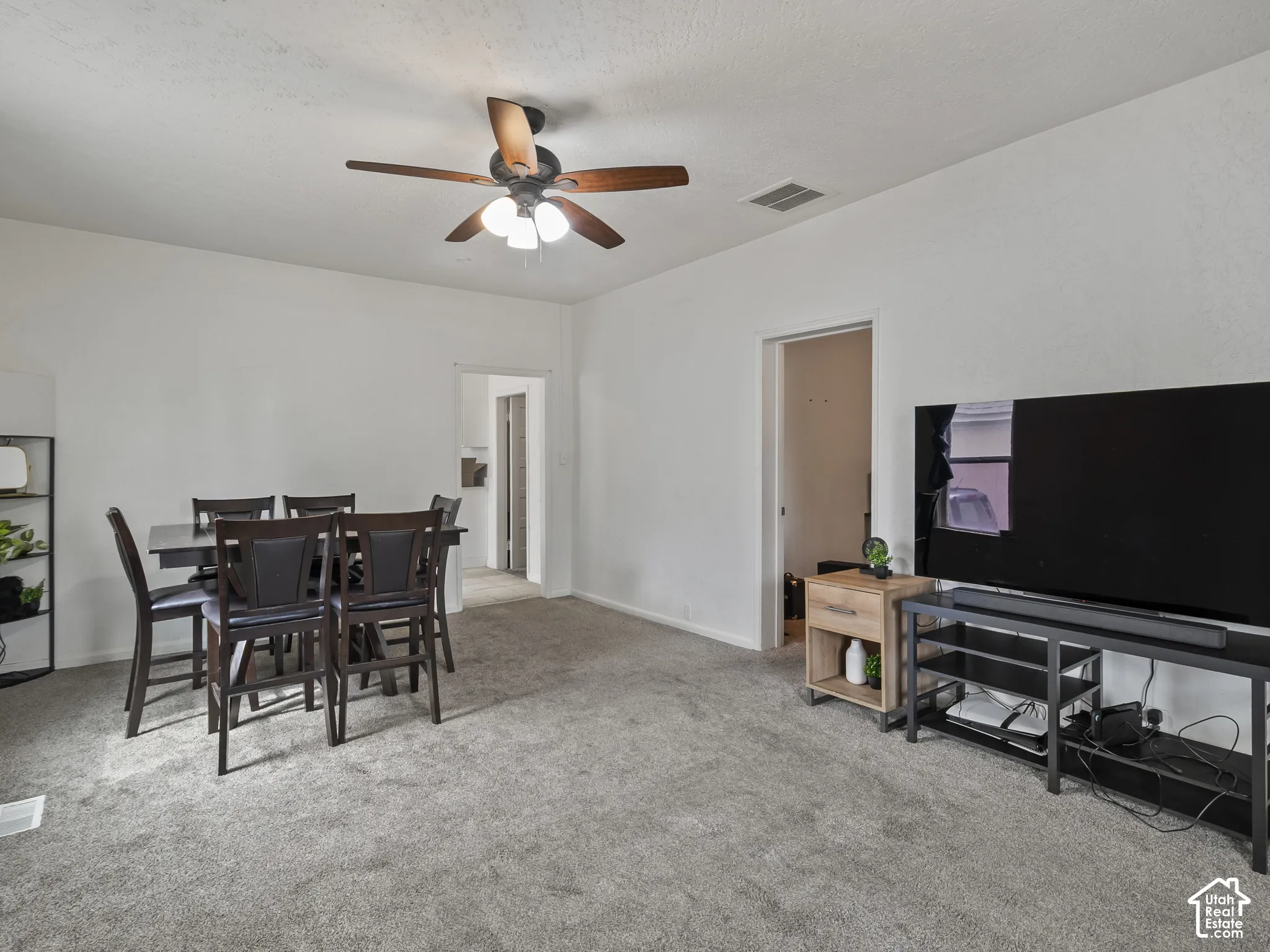 Dining space with light carpet and a ceiling fan