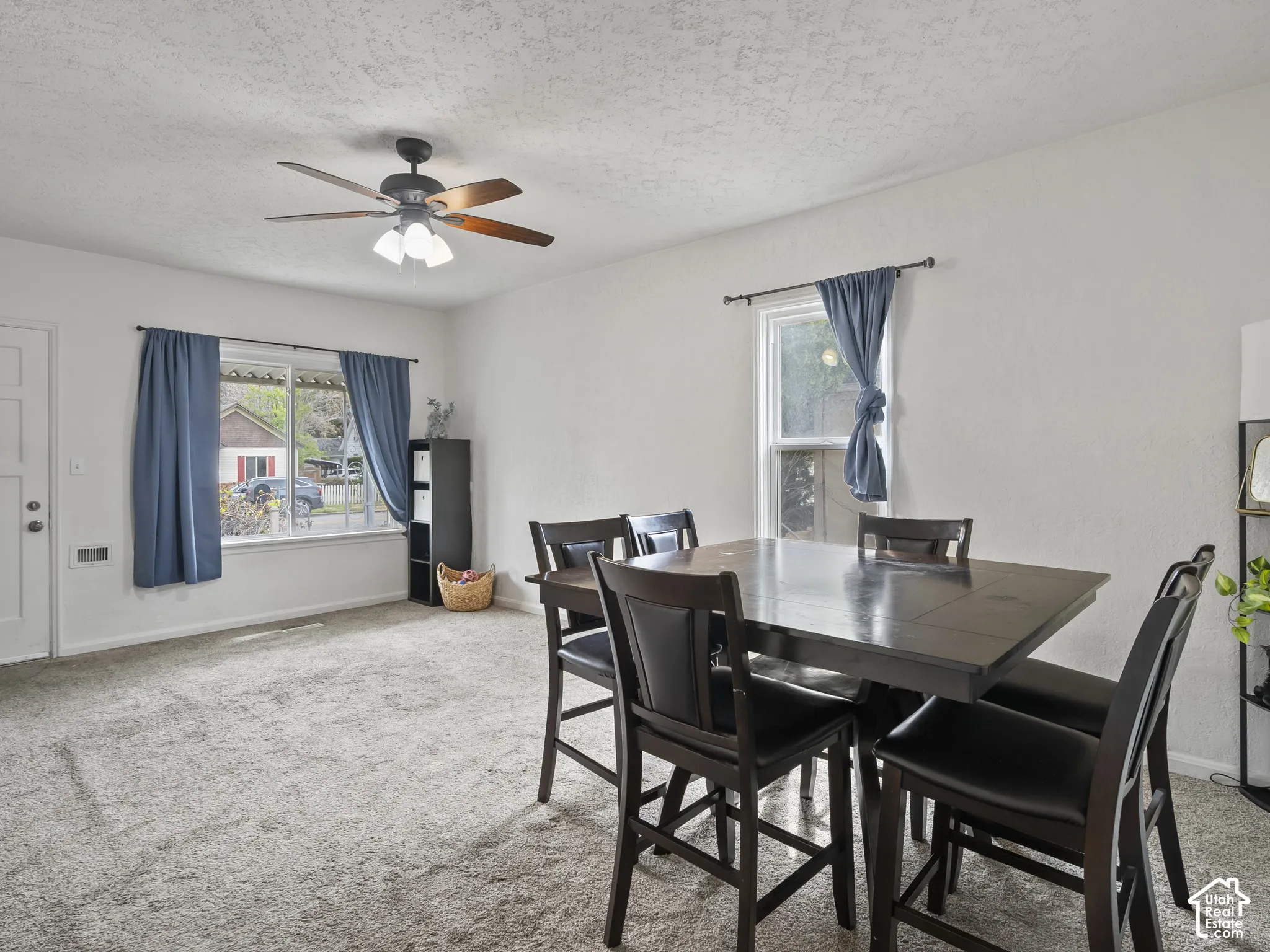 Dining room with light carpet, healthy amount of natural light, a ceiling fan, and a textured ceiling