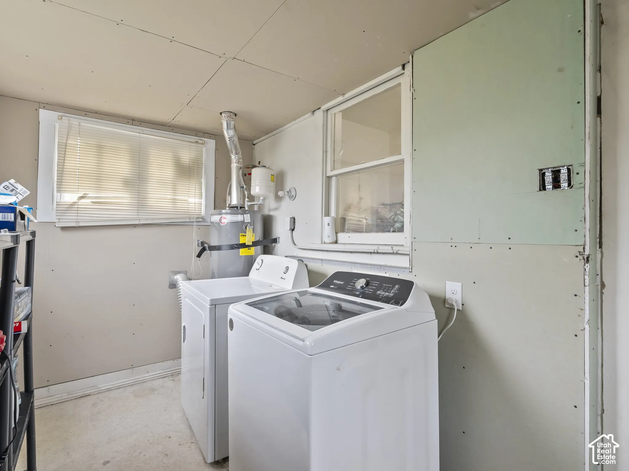 Laundry area featuring washing machine and clothes dryer, strapped water heater, and unfinished concrete floors