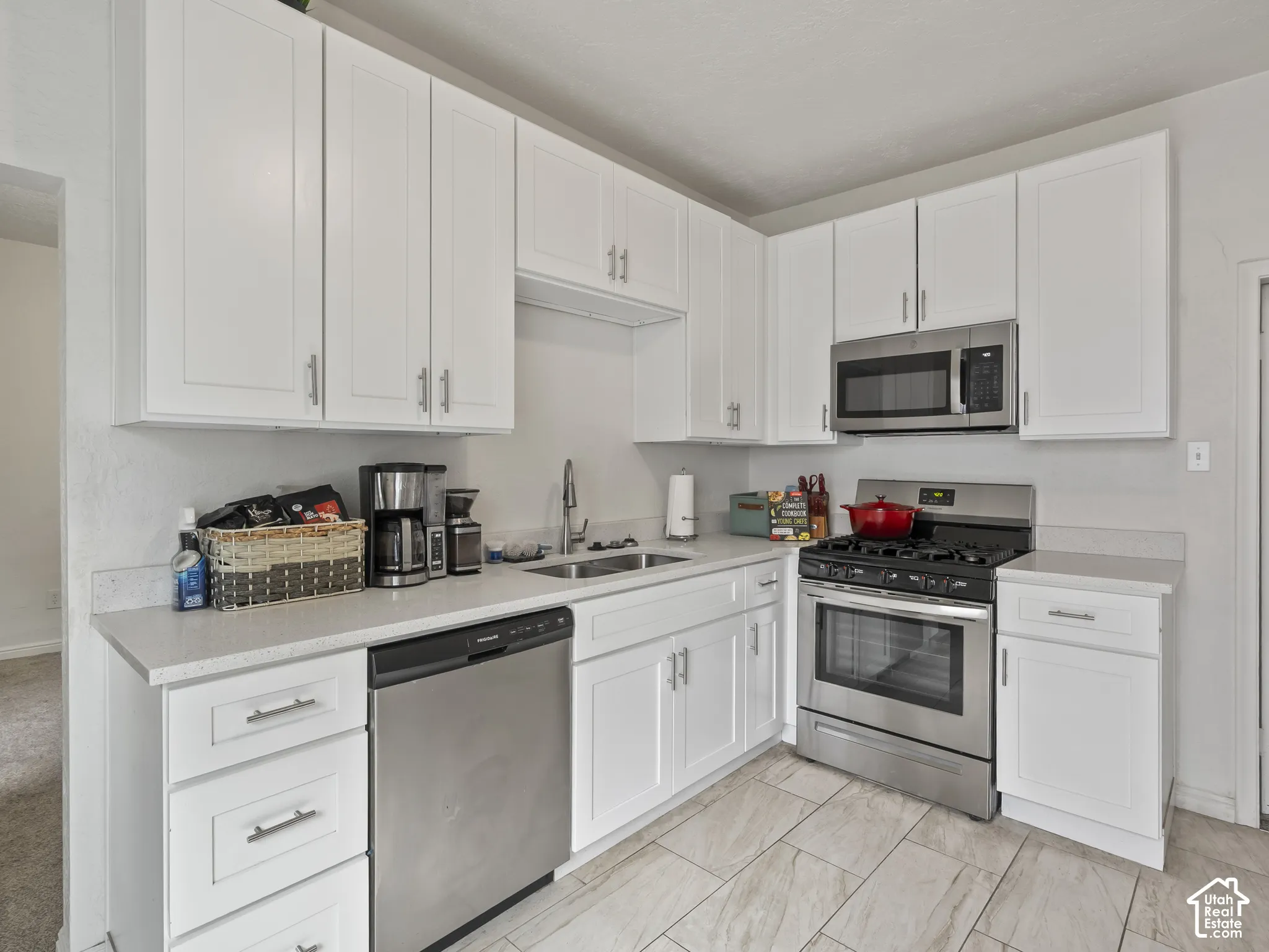 Kitchen with white cabinets, stainless steel appliances, and light stone counters