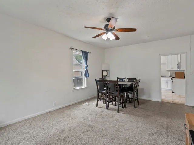 Dining room featuring light colored carpet, a ceiling fan, and a textured ceiling
