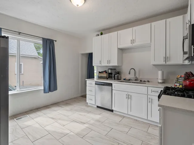 Kitchen with white cabinetry, stainless steel appliances, light stone counters, and a textured ceiling