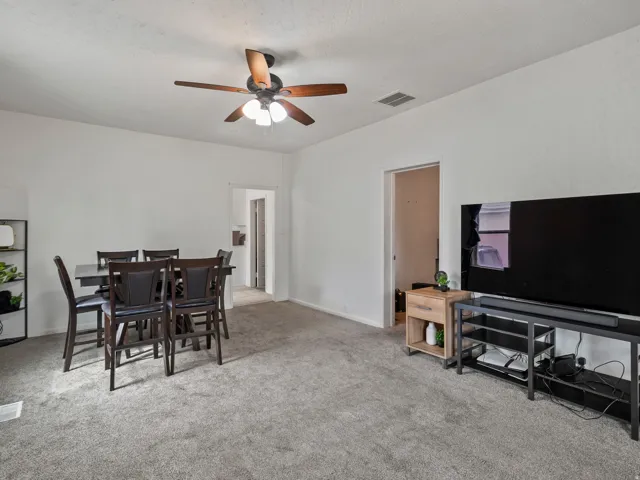 Dining space with light carpet and a ceiling fan