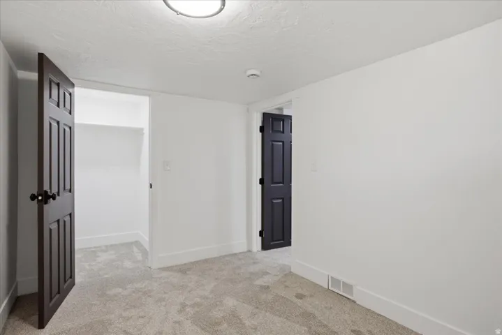 Unfurnished room featuring light carpet, a textured ceiling, and a smoke detector