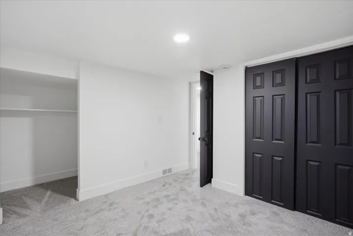 Unfurnished bedroom with light colored carpet and baseboards