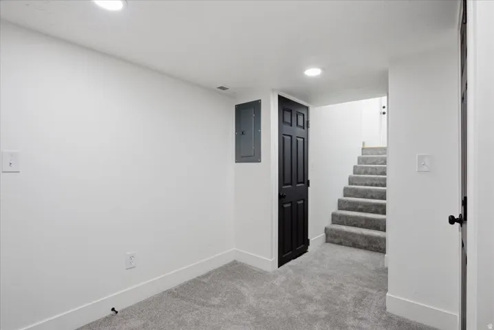 Finished below grade area with light colored carpet, electric panel, and recessed lighting