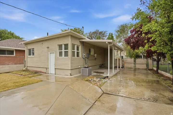 Rear view of house featuring a gate, concrete driveway, a patio, and a carport