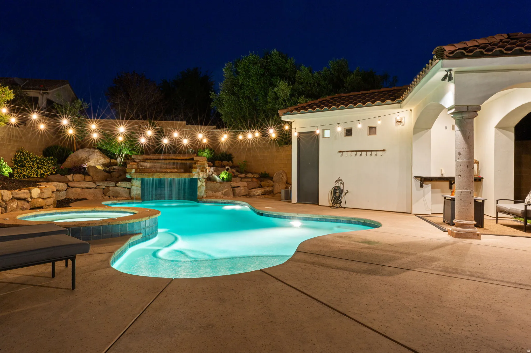 Resort-style backyard featuring a custom-shaped pool, integrated spa, and rock waterfall