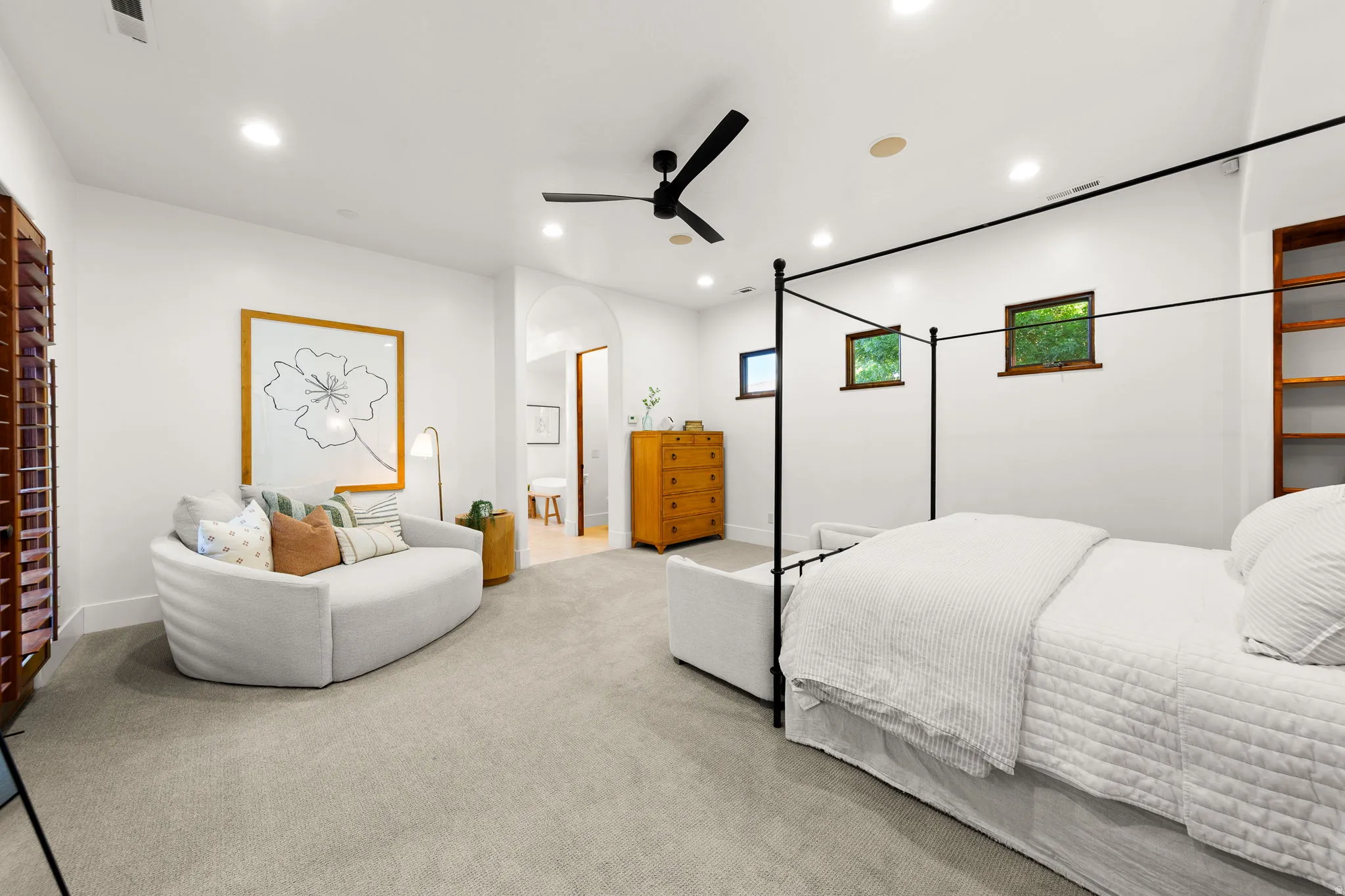 Carpeted bedroom featuring a ceiling fan, arched walkways, recessed lighting, and connected bathroom