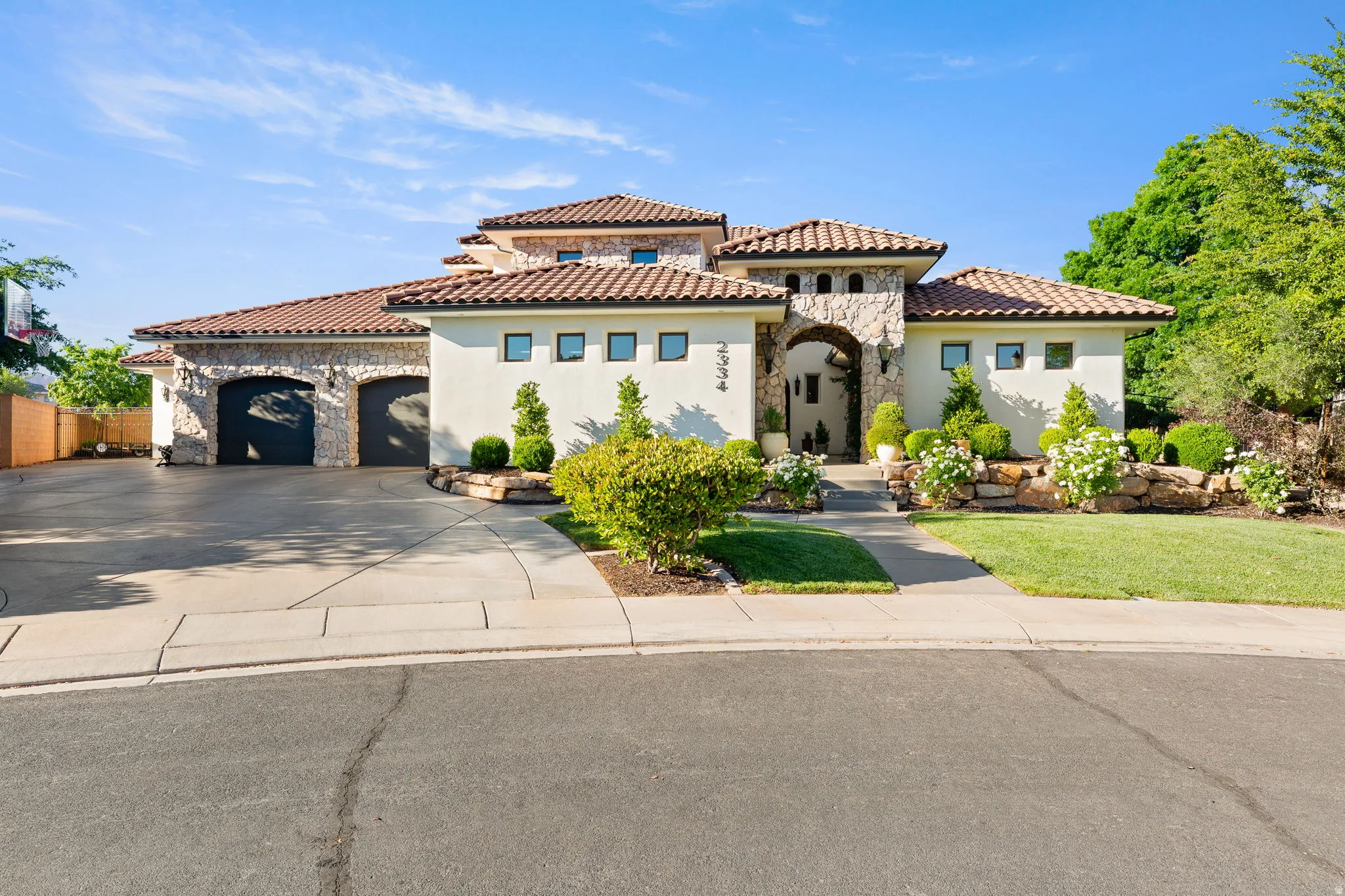 Mediterranean / spanish home featuring stone siding, an attached garage, concrete driveway, and stucco siding