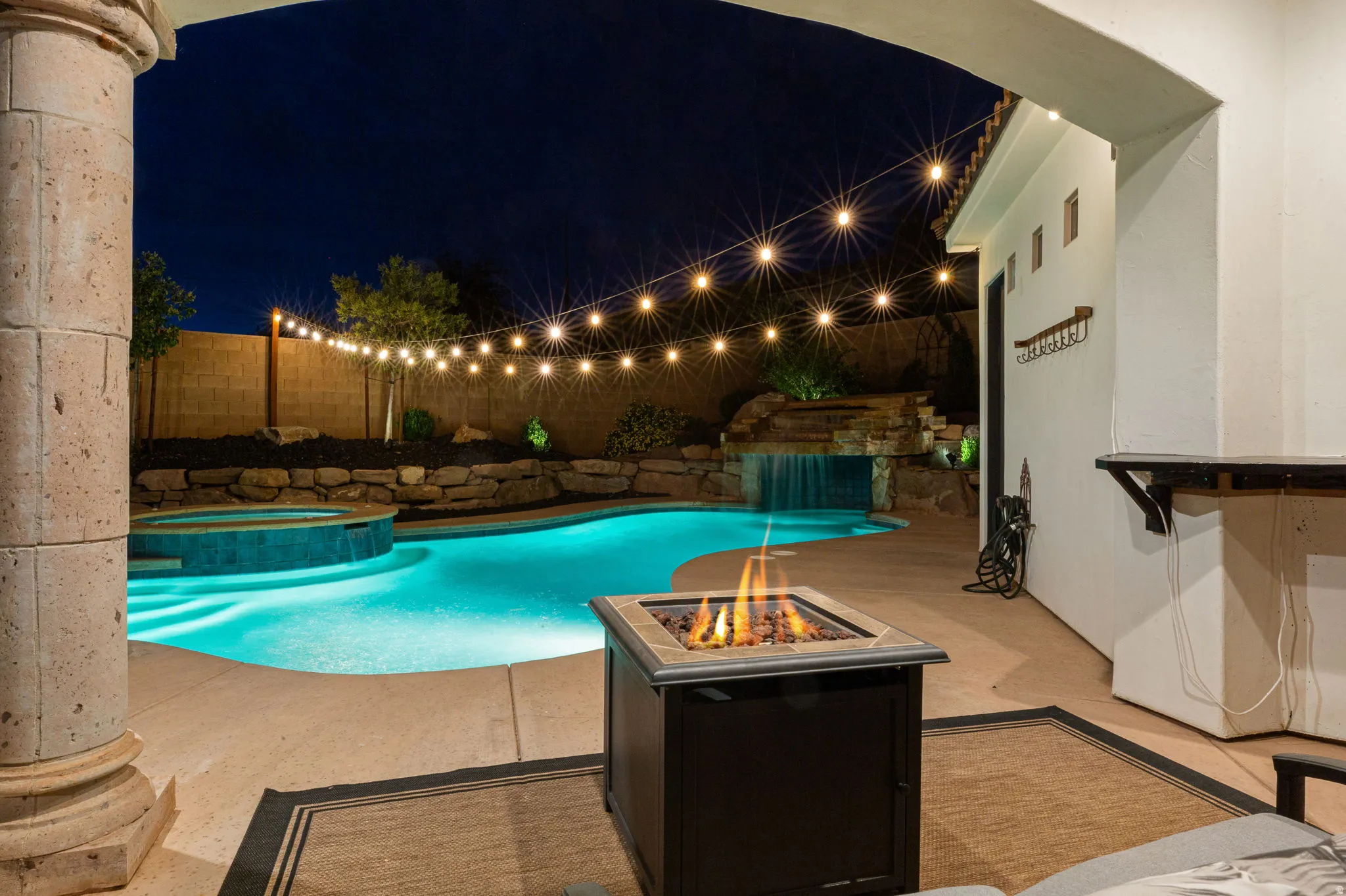 Backyard oasis featuring a swimming pool, integrated spa, and rock waterfall