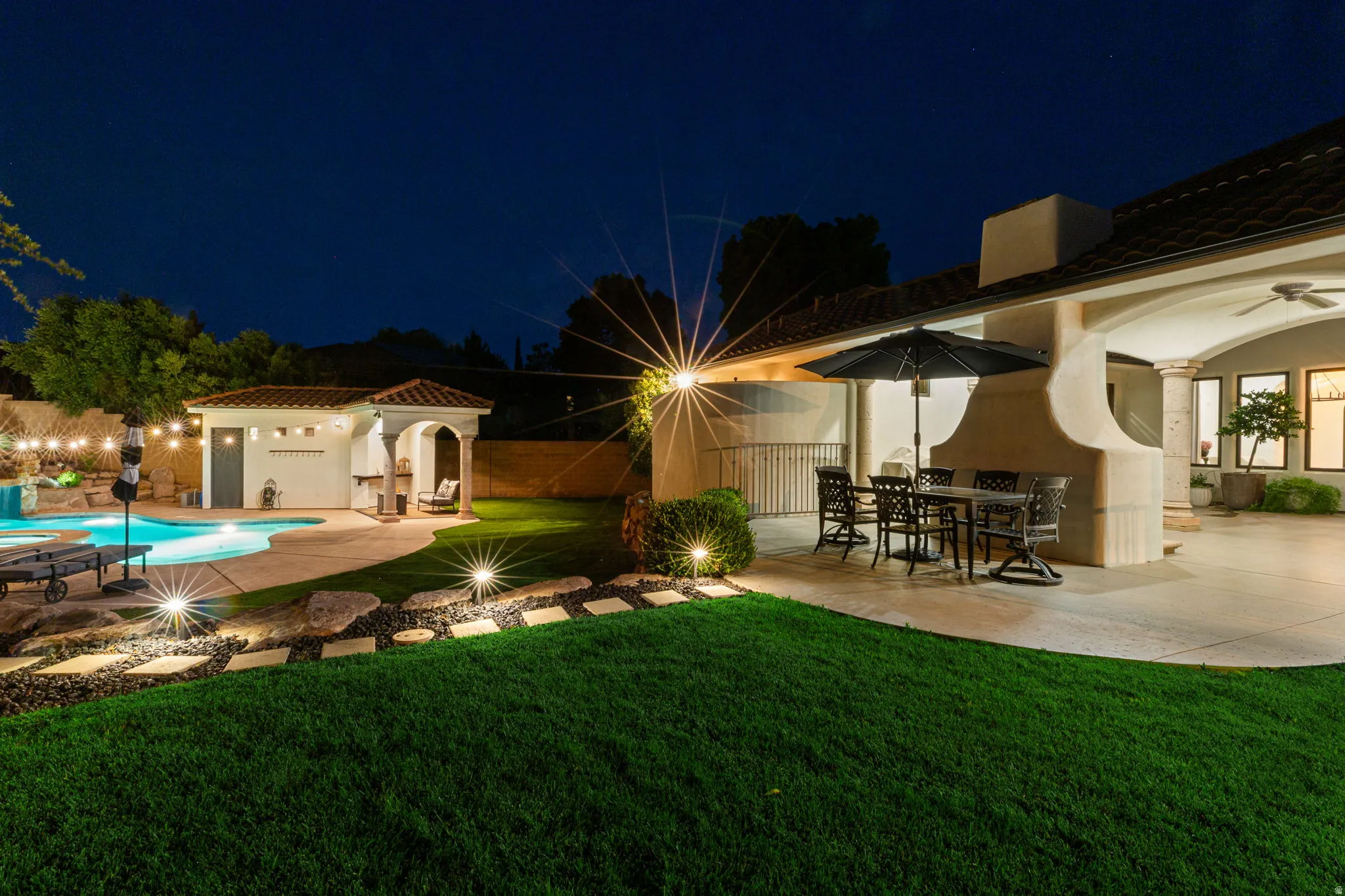Expansive backyard featuring a freeform swimming pool, integrated spa, and a dedicated pool house with a covered patio