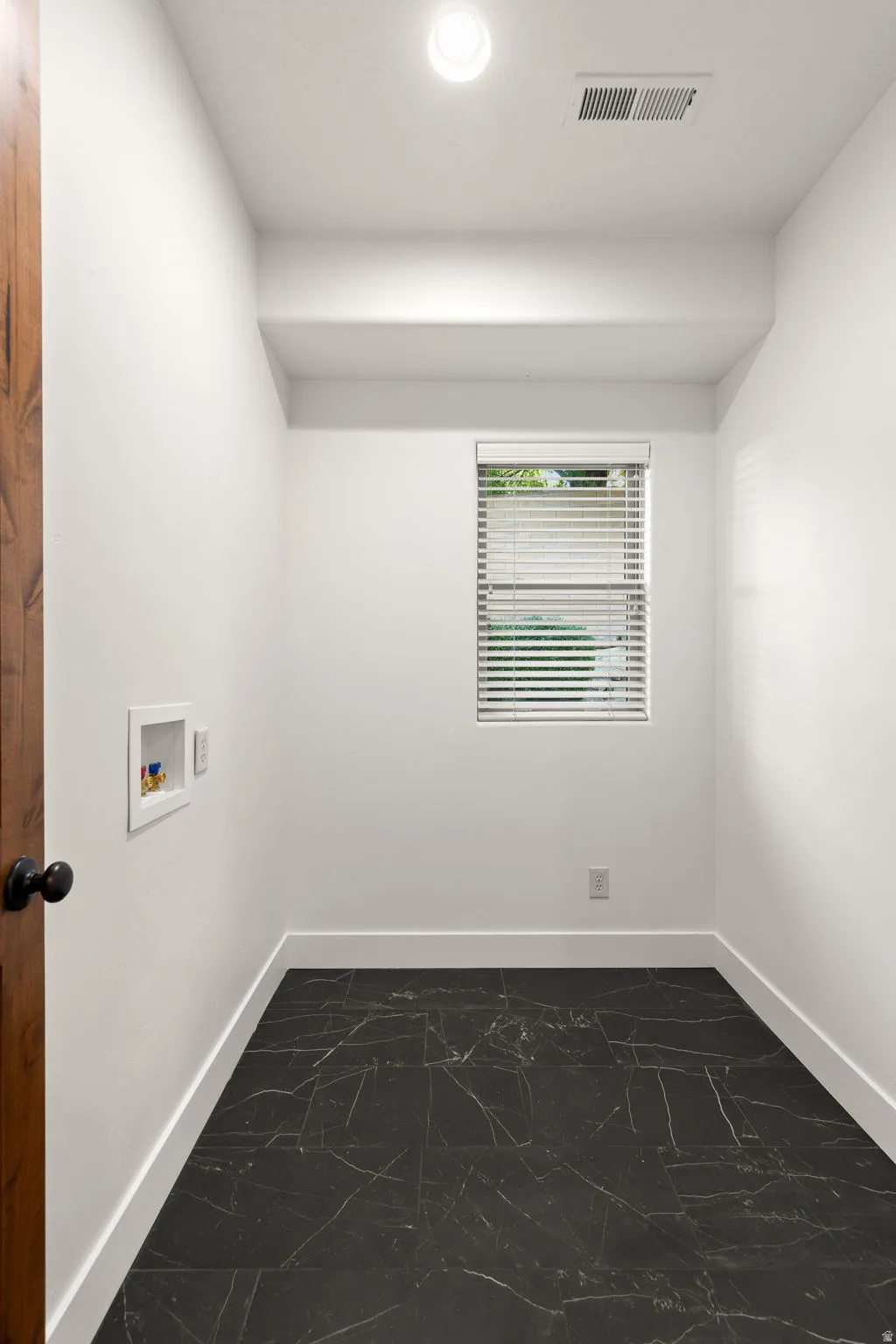 Laundry room with hookup for a washing machine and dark marble finish flooring