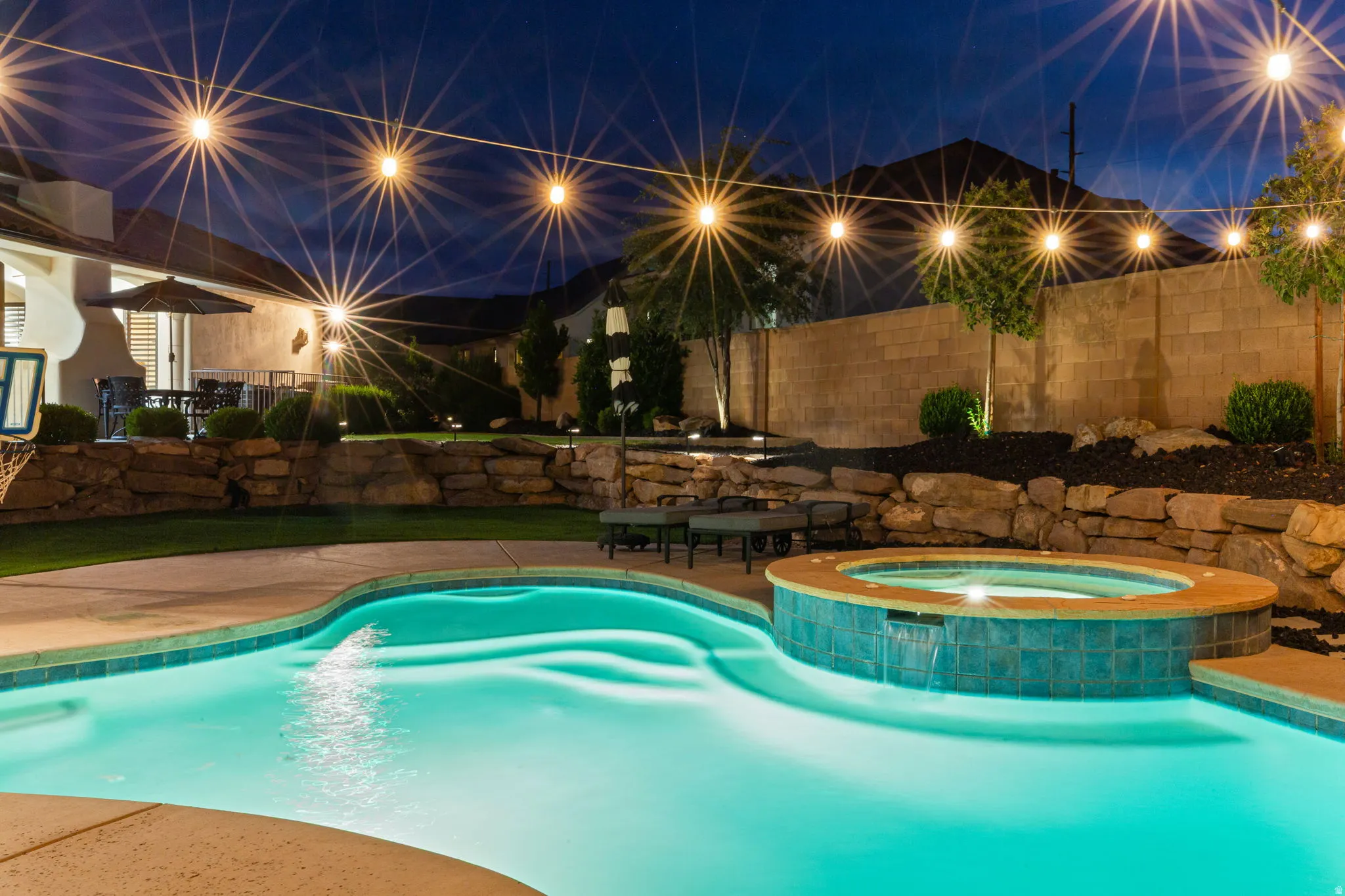 Backyard oasis featuring a curvilinear swimming pool and integrated spa with a waterfall feature