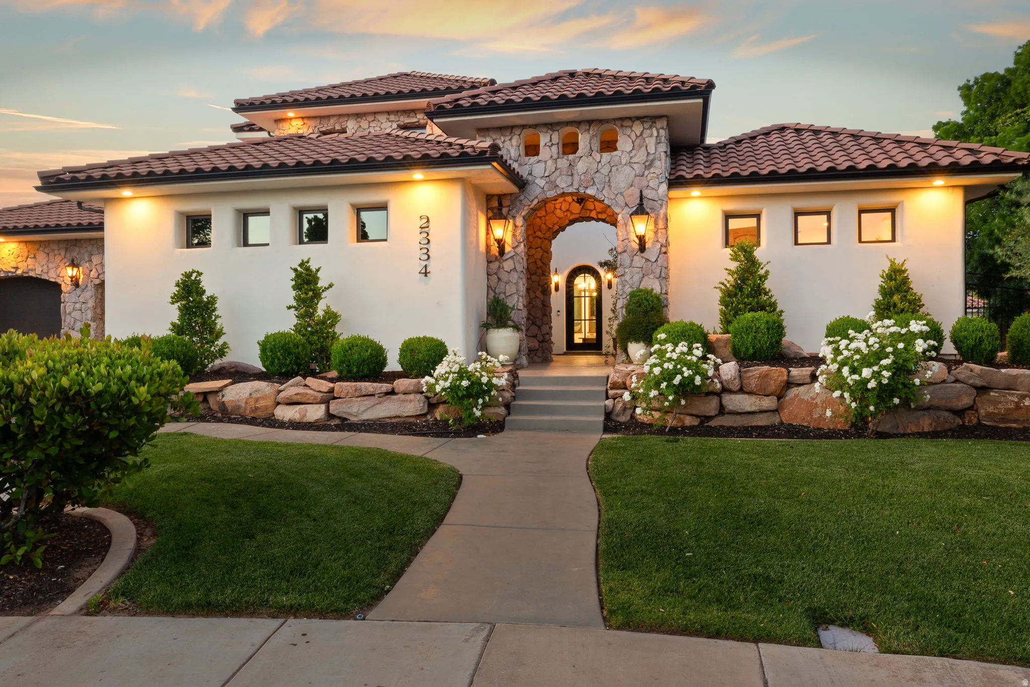 Mediterranean / spanish home with stone siding, a lawn, and stucco siding