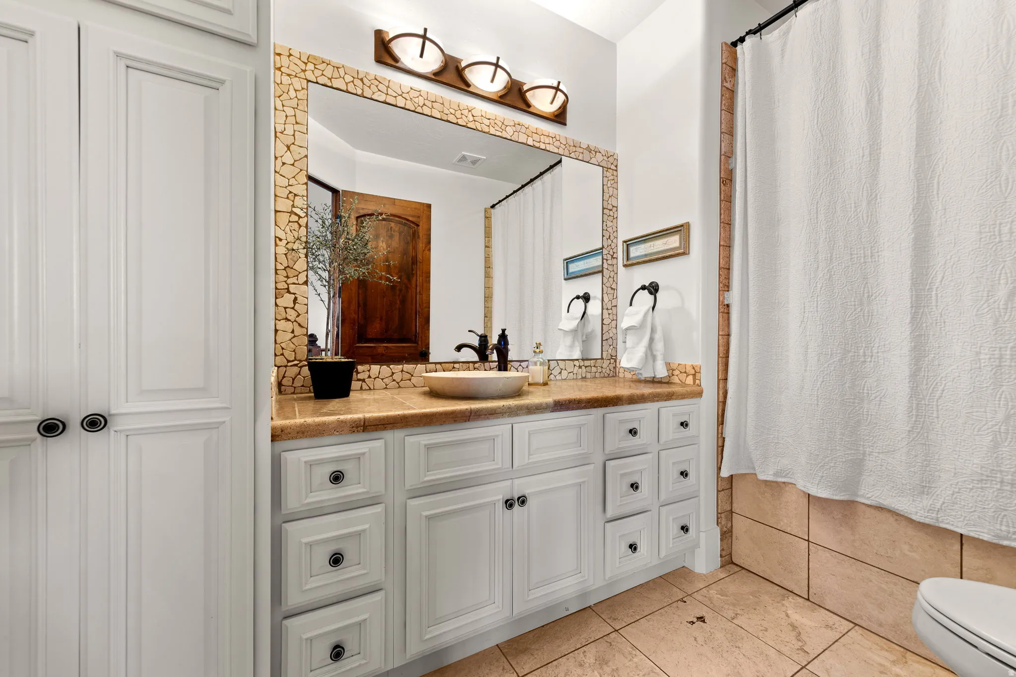 Full bathroom featuring vanity, light tile patterned floors, and a shower with shower curtain