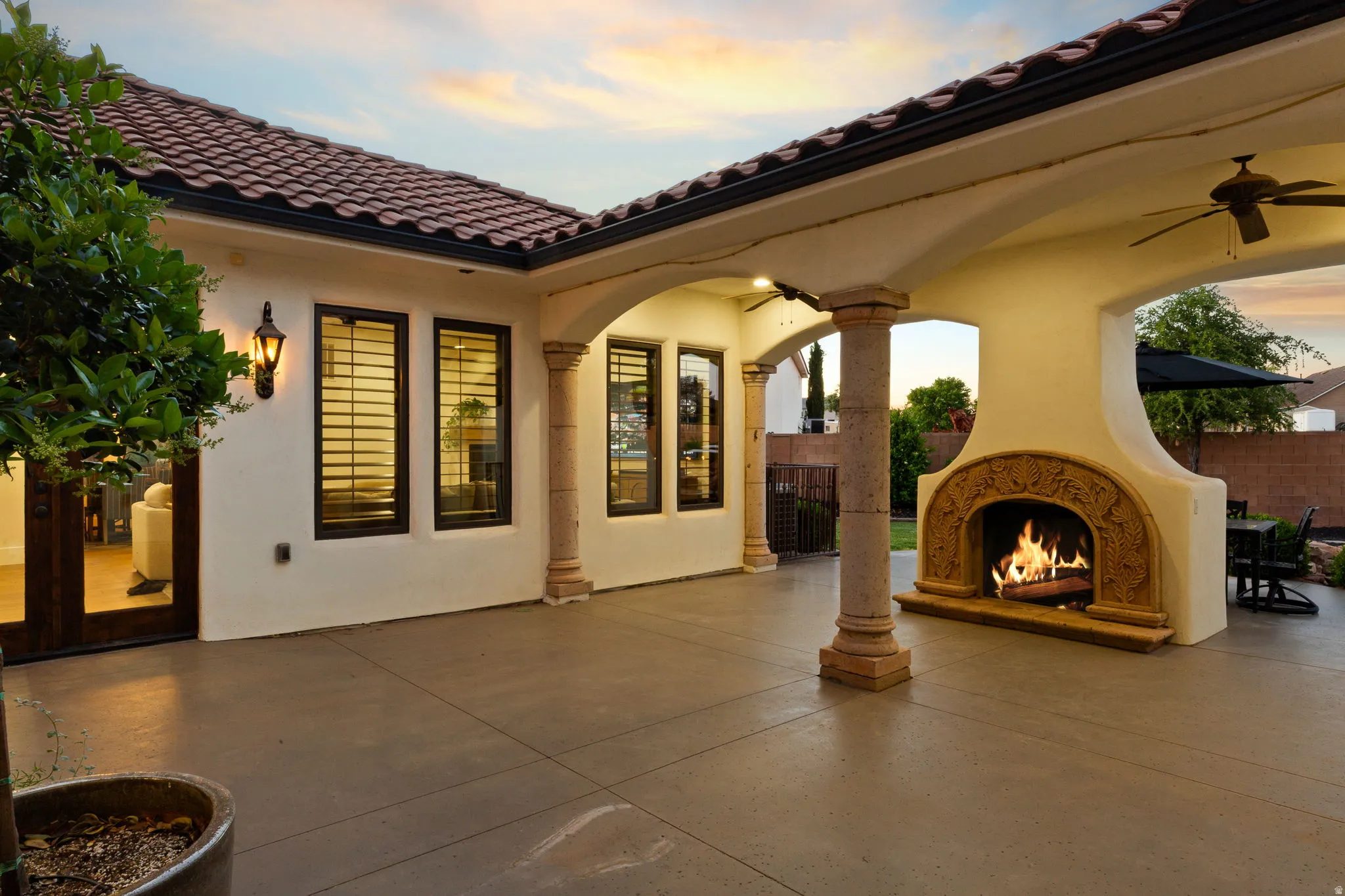 View of patio featuring a warm lit fireplace and ceiling fan