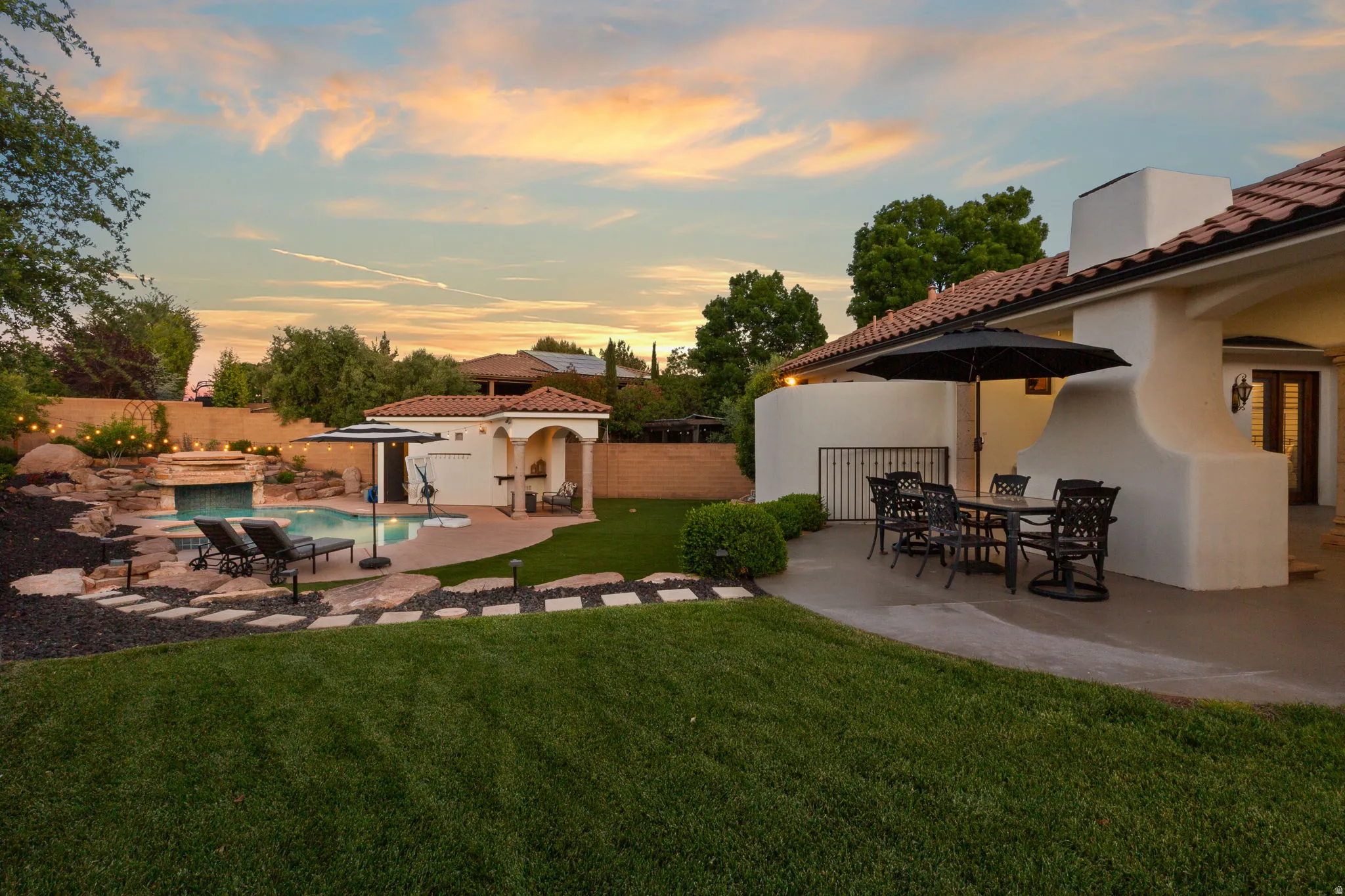 Fenced backyard with a patio, outdoor dining area, and an outbuilding