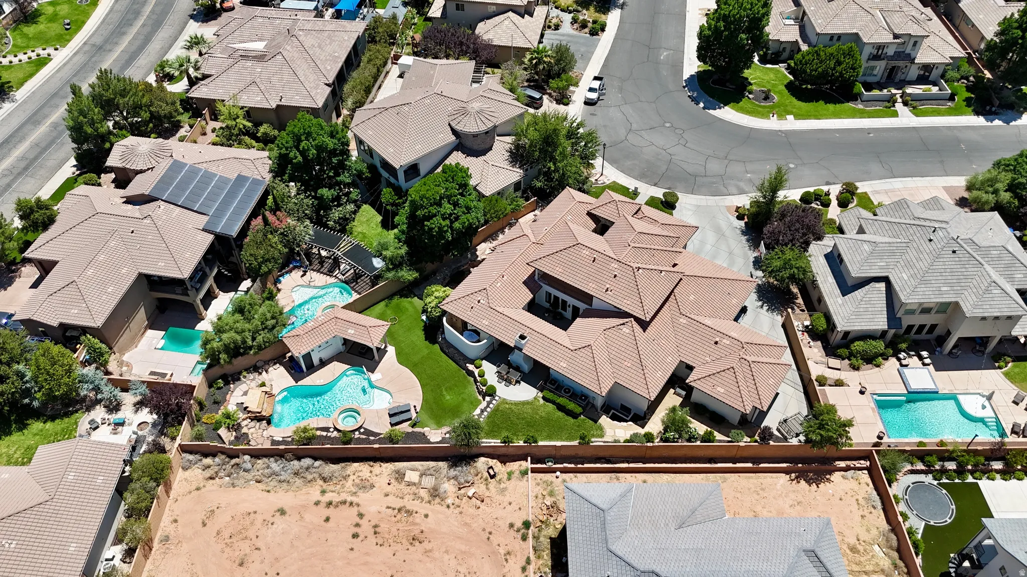 Expansive property featuring a multi-level tile roof, multiple swimming pools, a spa, and mature landscaping