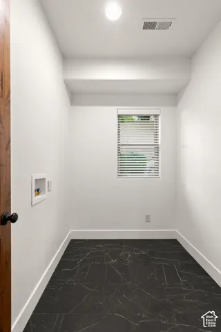 Laundry room with hookup for a washing machine and dark marble finish flooring