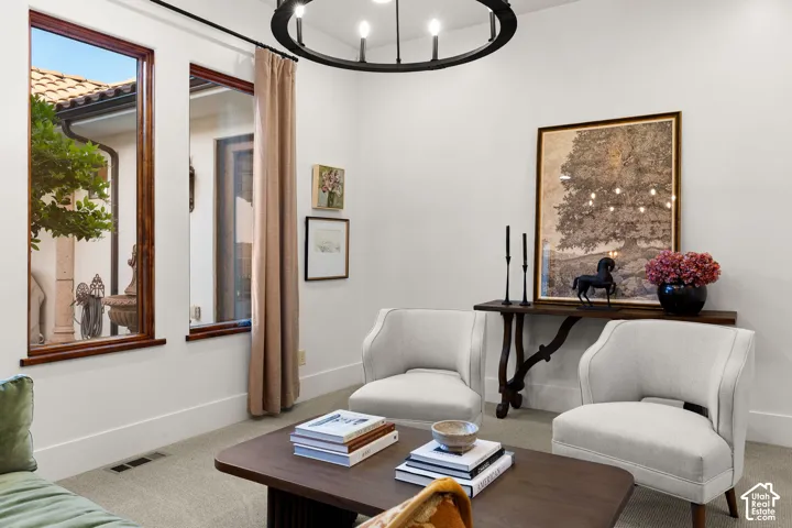 Sitting room featuring suspended lighting and carpet