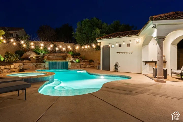 Resort-style backyard featuring a custom-shaped pool, integrated spa, and rock waterfall