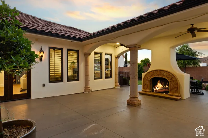 View of patio featuring a warm lit fireplace and ceiling fan