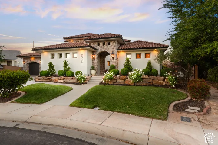 Mediterranean / spanish house featuring stone siding, a front yard, stucco siding, and a tile roof