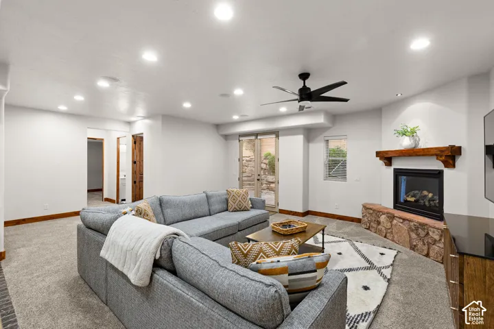 Carpeted living area featuring a ceiling fan, recessed lighting, and a glass covered fireplace