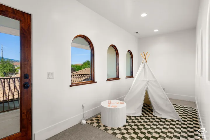 Recreation room with light colored carpet and recessed lighting