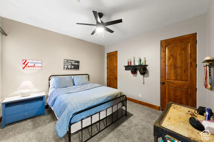 Carpeted bedroom featuring baseboards and ceiling fan