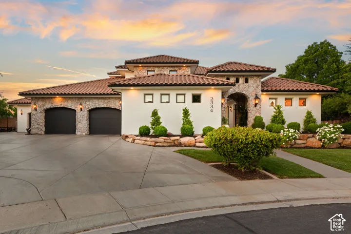 Mediterranean / spanish house featuring stone siding, an attached garage, concrete driveway, and stucco siding