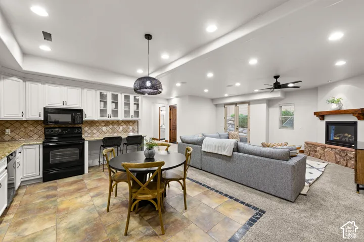 Dining room featuring recessed lighting, a glass covered fireplace, ceiling fan, a raised ceiling, and light colored carpet