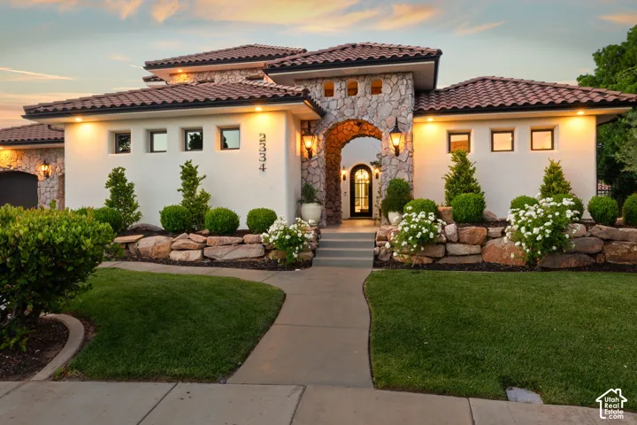 Mediterranean / spanish home with stone siding, a lawn, and stucco siding