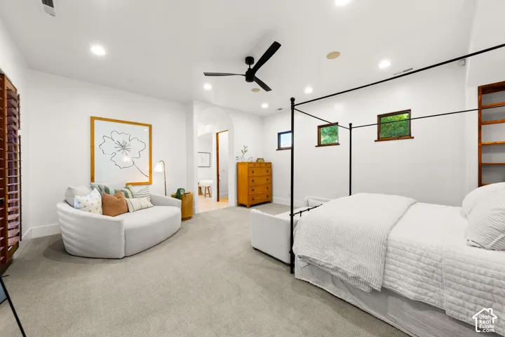 Carpeted bedroom featuring a ceiling fan, arched walkways, recessed lighting, and connected bathroom