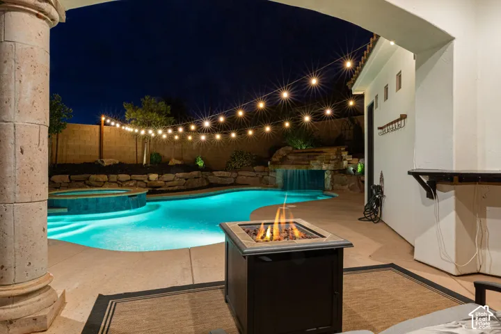 Backyard oasis featuring a swimming pool, integrated spa, and rock waterfall