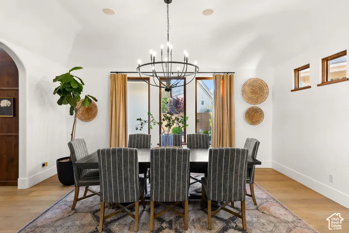 Dining room featuring light wood-style floors, arched walkways, and a chandelier