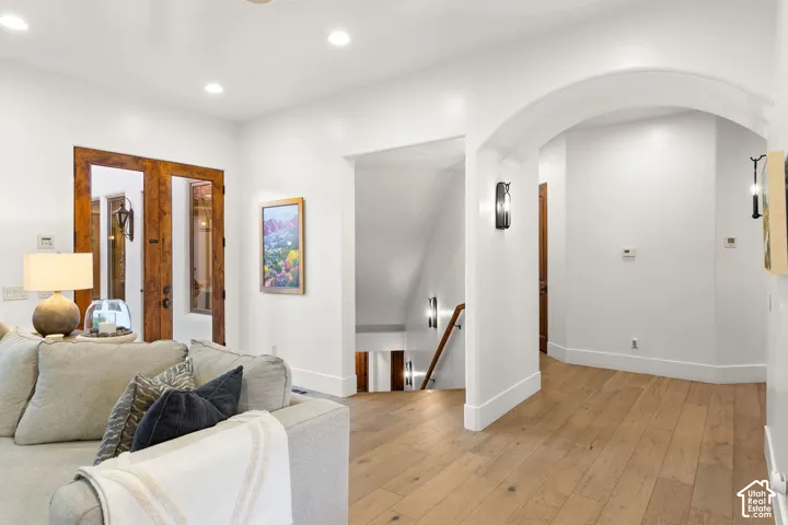 Living area with light wood-type flooring, recessed lighting, and arched walkways