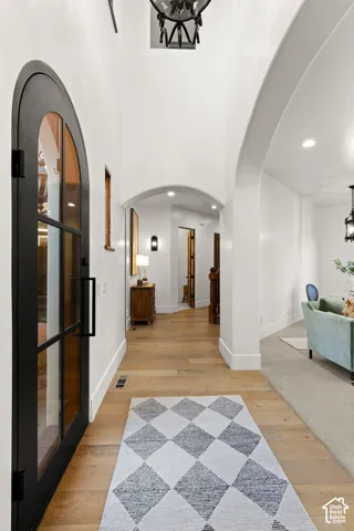 Foyer featuring arched walkways, light wood finished floors, and suspended lighting