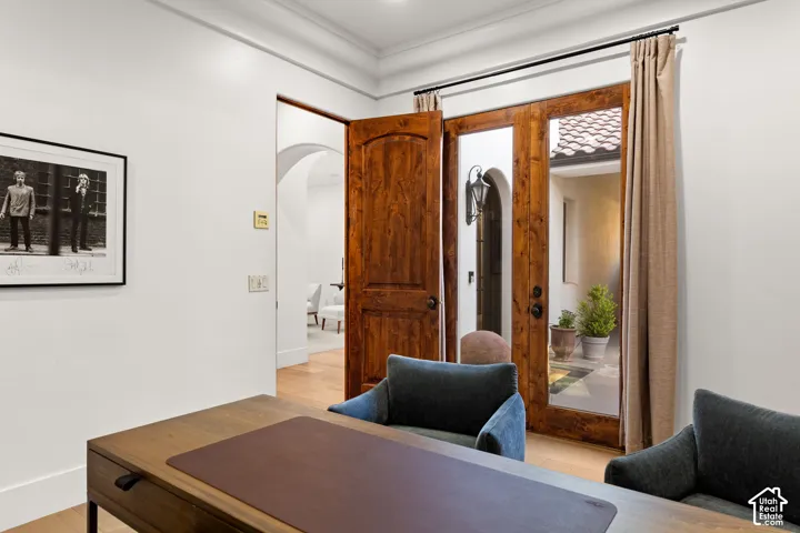 Office space featuring arched walkways, light wood-style floors, and crown molding