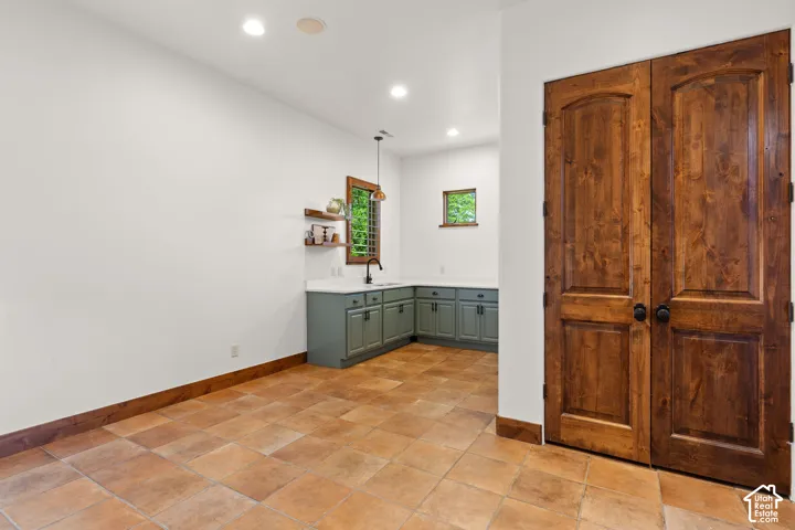 Bar featuring light countertops, open shelves, decorative light fixtures, and green cabinets