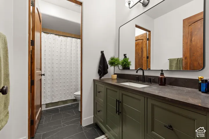 Bathroom with vanity, a shower with shower curtain, and dark marble finish floors