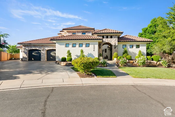 Mediterranean / spanish home featuring stone siding, an attached garage, concrete driveway, and stucco siding