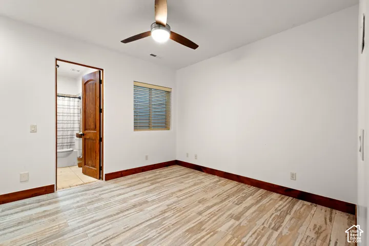 Unfurnished bedroom with light wood-style floors, ceiling fan, and connected bathroom