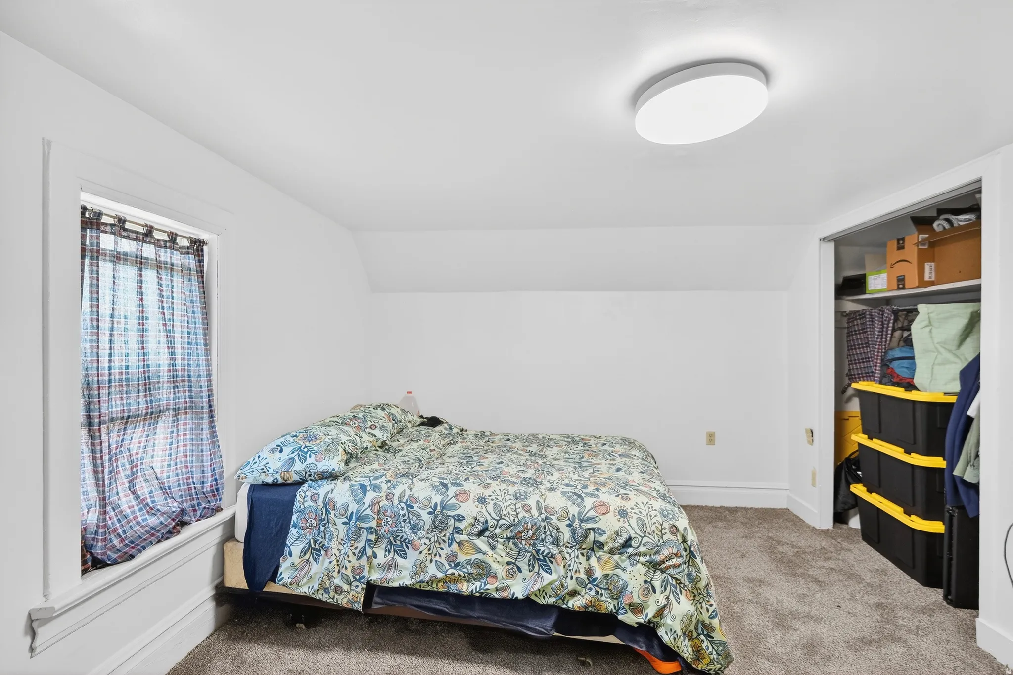 Bedroom with light colored carpet and vaulted ceiling