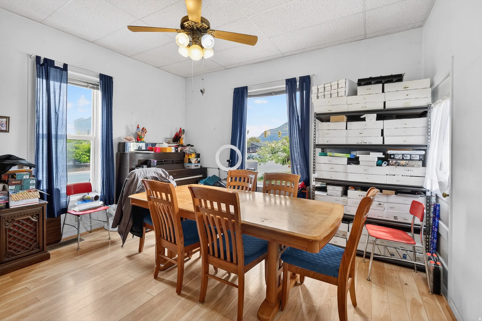 Dining area featuring ceiling fan, light wood finished floors, and a drop ceiling