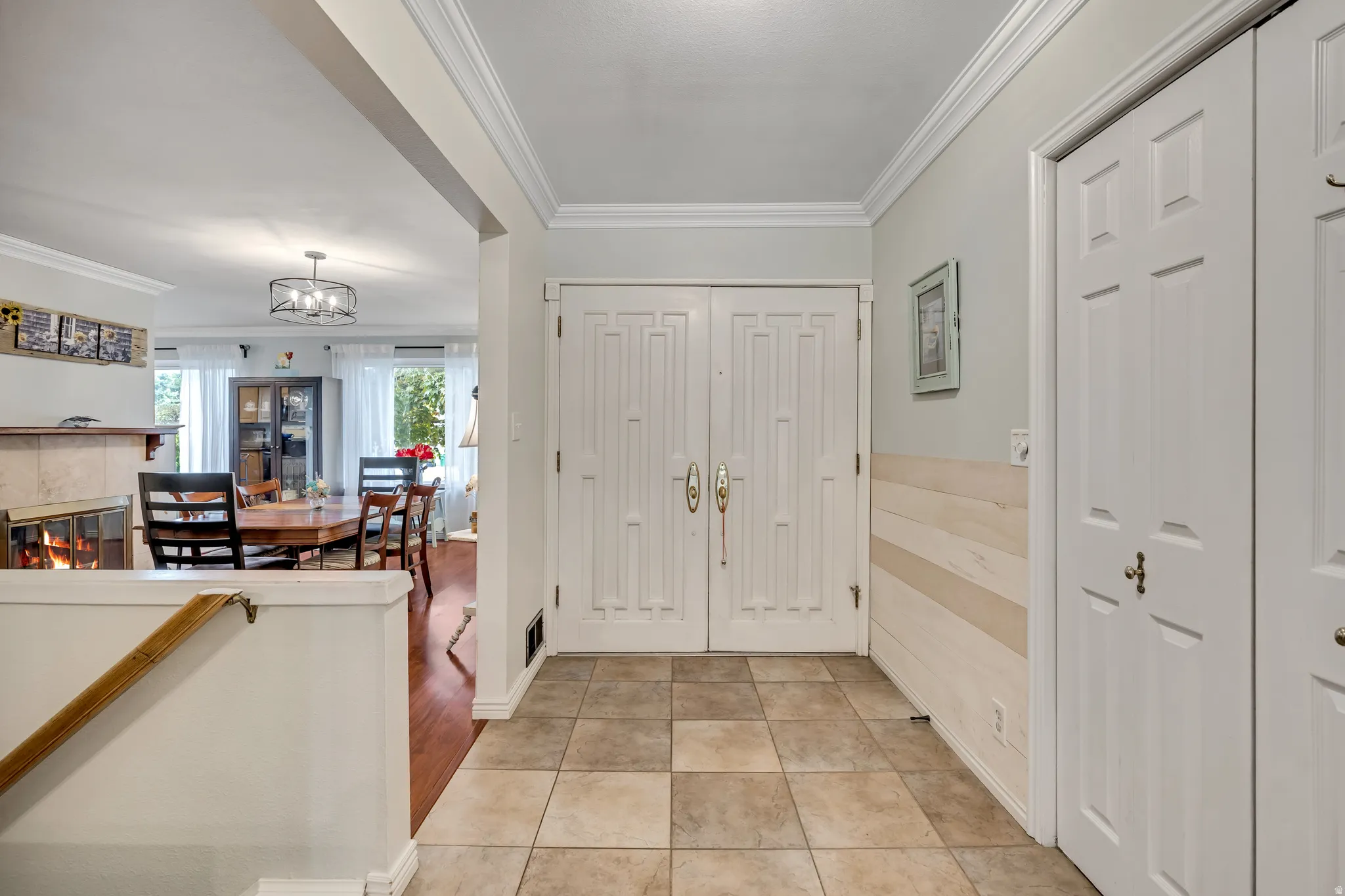 Foyer featuring crown molding, light tile patterned flooring, suspended lighting, and a tile fireplace