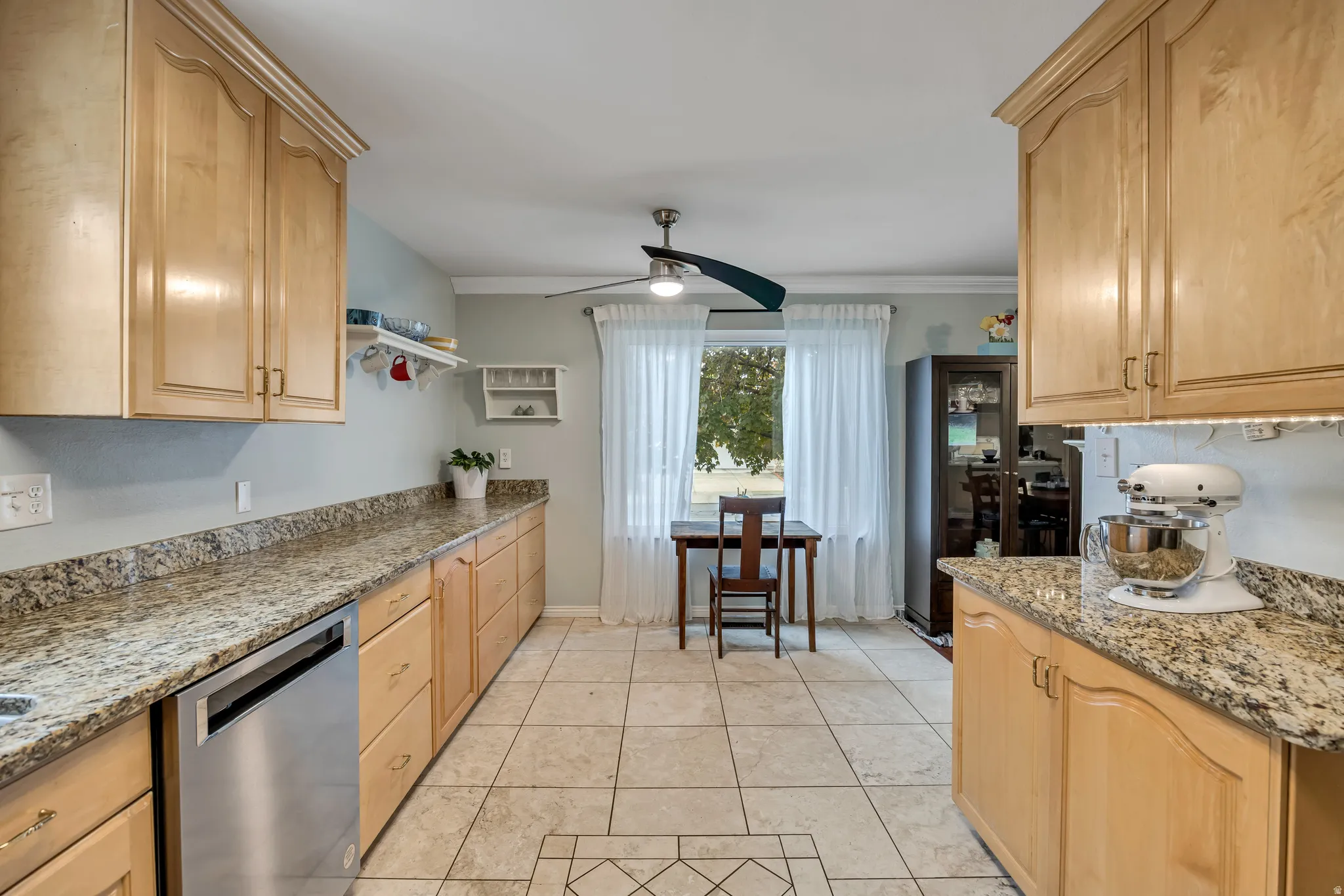 Kitchen featuring light stone countertops, light wood finish cabinets, dishwasher, and ceiling fan
