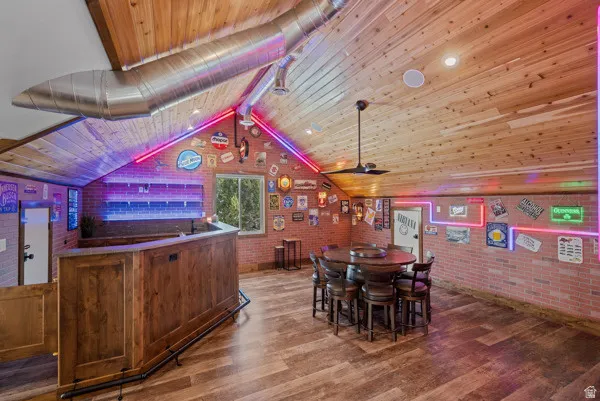 Dining area with brick wall, dark wood-style floors, wood ceiling, and a ceiling fan